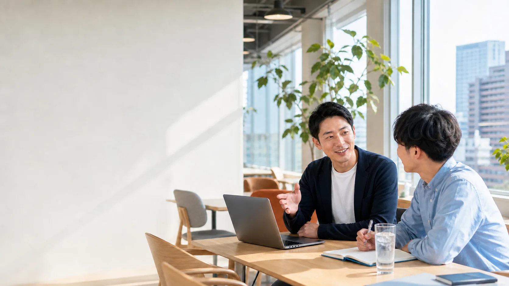 Hai người trao đổi công việc bên laptop trong văn phòng nhiều ánh sáng